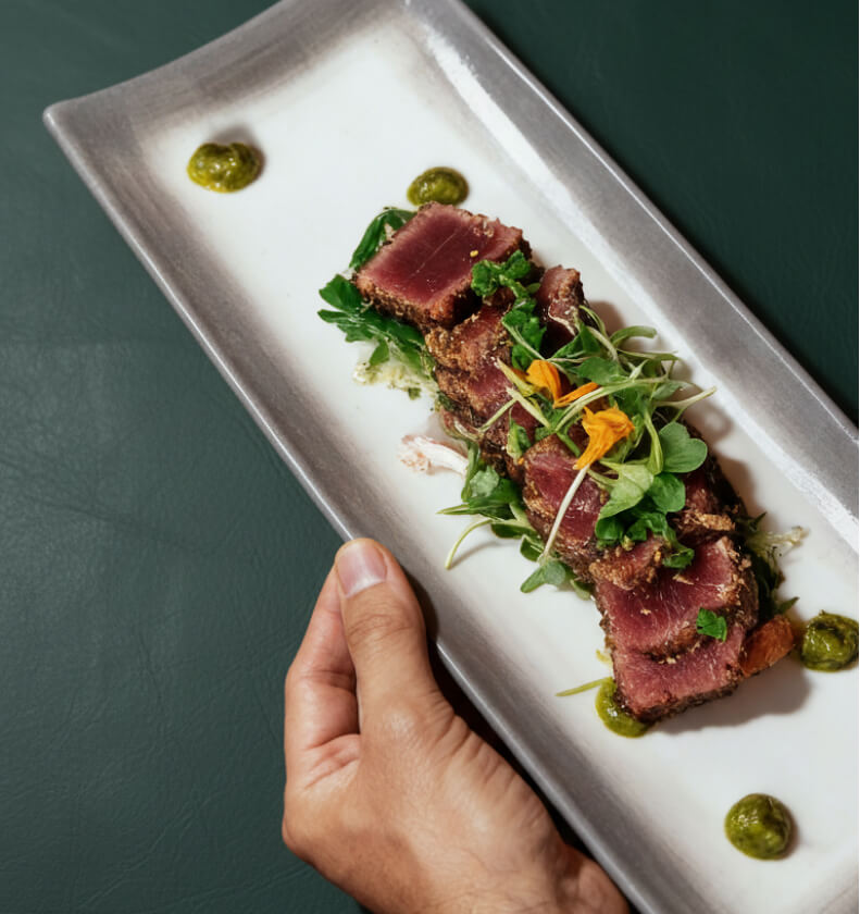 Tataki de atún con brotes verdes servido en plato alargado