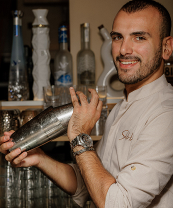 Bartender de Sabbia sonriendo mientras agita una coctelera